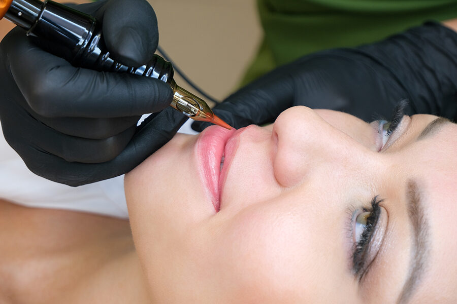 Young woman having permanent makeup on her lips at the beauticia Imagen de Young woman having permanent makeup on her lips at the beauticia