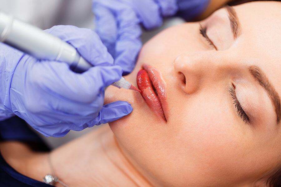 Young woman having permanent makeup on lips in beautician salon. close up Imagen de Young woman having permanent makeup on lips in beautician salon. close up